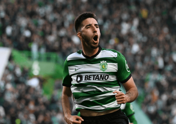 Jugador de fútbol celebrando un gol con la camiseta del Sporting de Lisboa, en un estadio lleno de aficionados.
